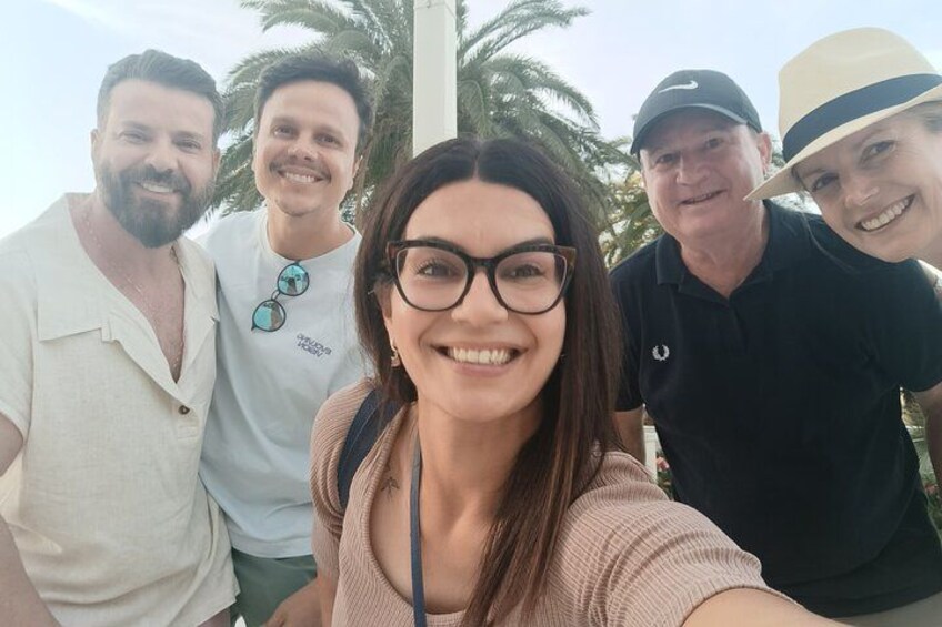 A group of people outdoors with palm trees in the background. 1