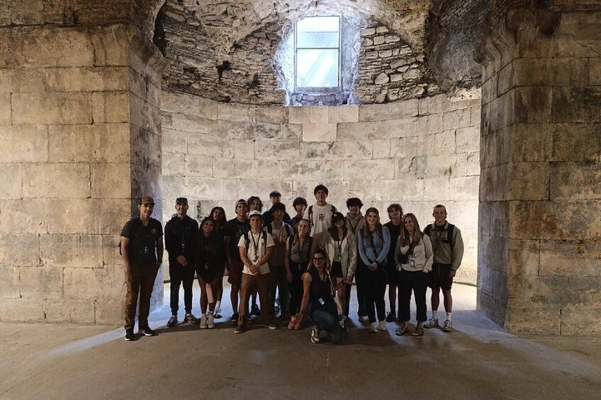 A group of people standing in a stone-walled room with a window. 4