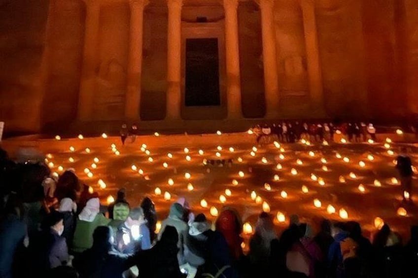 Gran multitud de personas en un edificio histórico con hileras de velas. 2