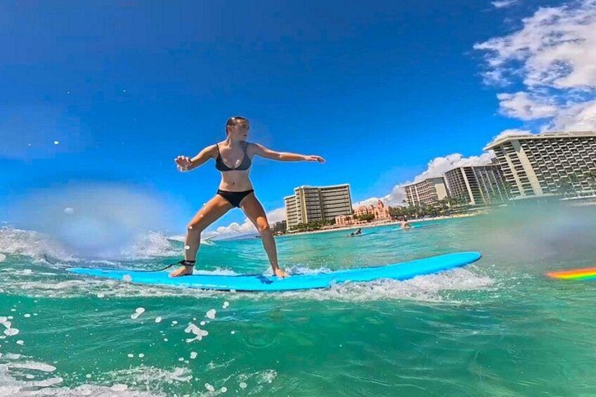 En person surfer på en bølge med en bysilhuet i baggrunden. 2