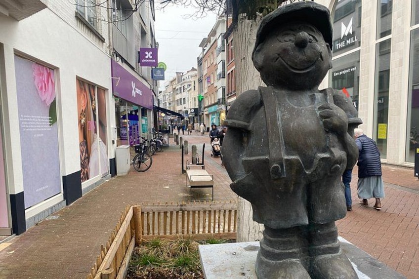 A statue of a figure with a hat and boots, a flower-adorned shop, and a building with a sign that reads 'THE MILL'. 4