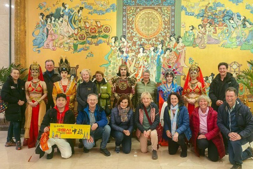 A group of people posing in front of a mural with traditional Chinese artwork. 3