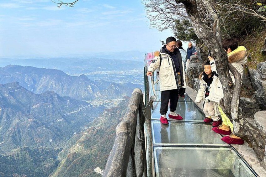 A glass bridge with people walking on it, overlooking a mountainous landscape. 4