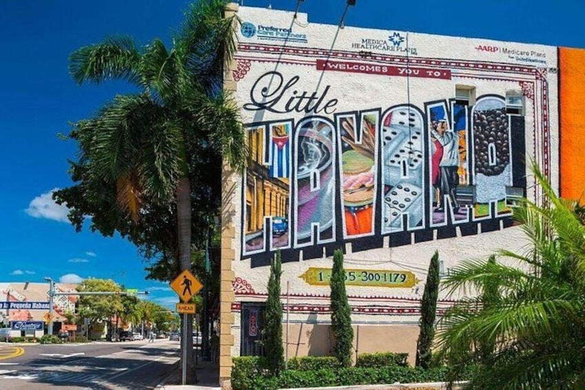 A colorful mural on a building with palm trees and a clear blue sky. 4