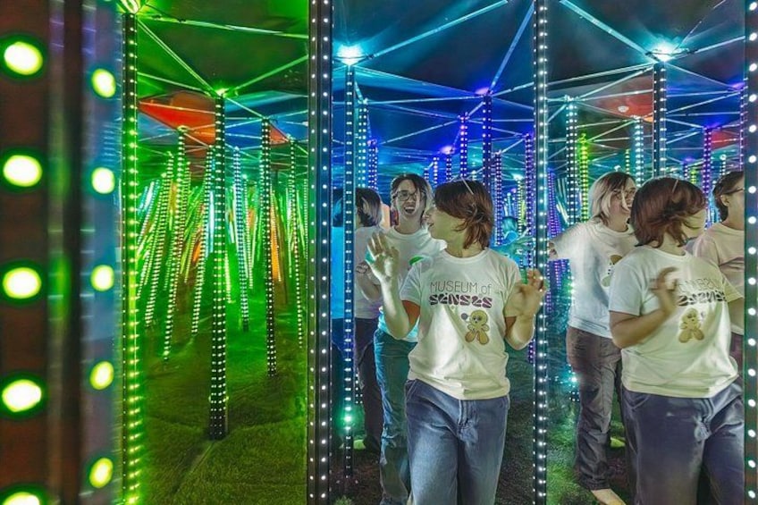 A group of people in a mirrored tunnel with colorful lights. 2