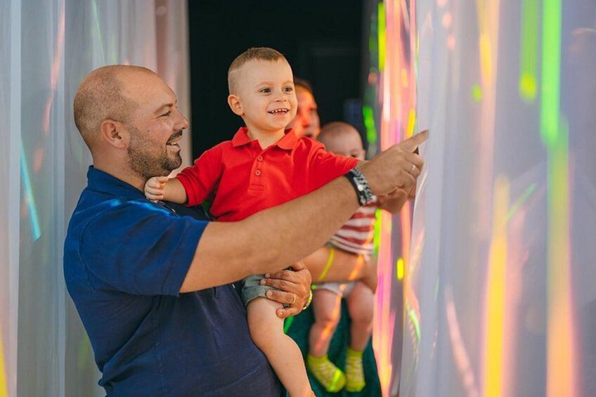 Un homme tenant un enfant, et pointant du doigt un spectacle lumineux aux couleurs vives. 3