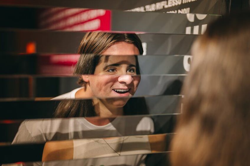 A person sitting at a table with a blurred face, a red sign in the background, and a partial view of another person. 5