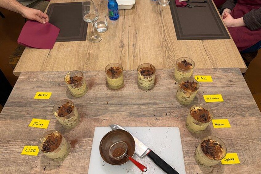 Et træbord med ni glas dessert, hver mærket med et navn. 2