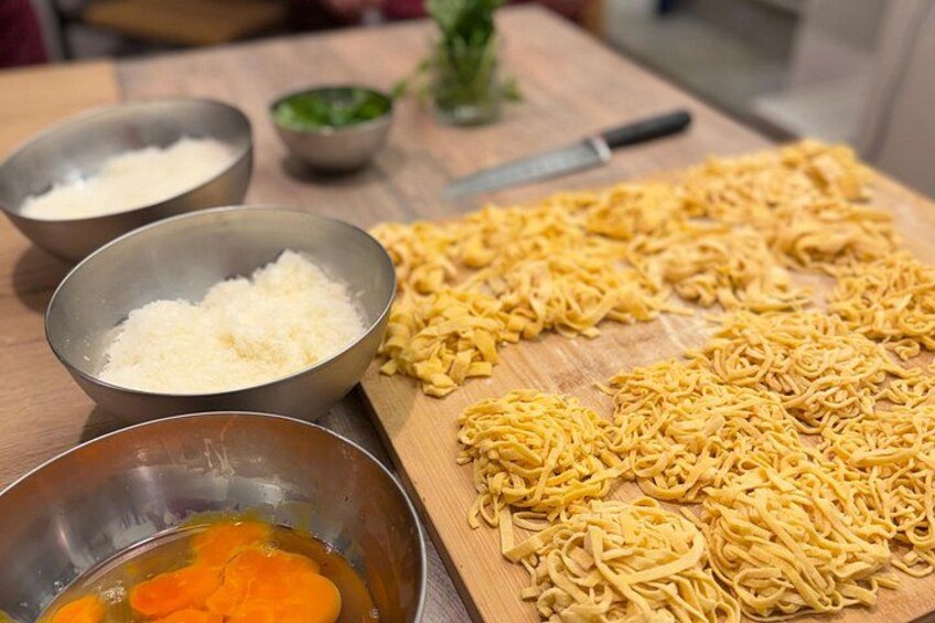 Et træbord dækket med skåle med ingredienser og udstrakte nudler. 3