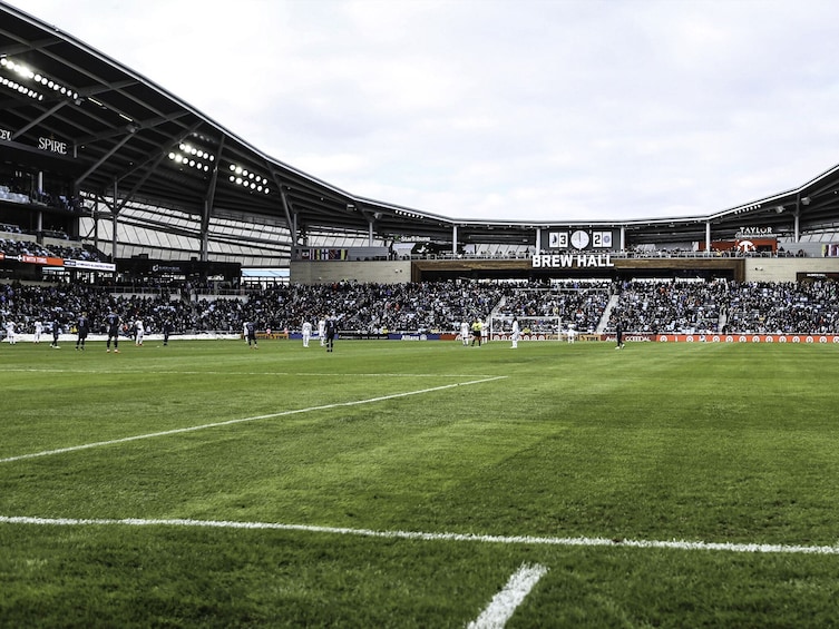 A football stadium with a scoreboard, advertisements, and a crowd. 5