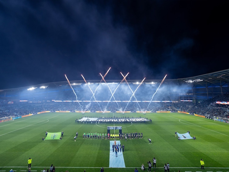 A football stadium at night with a large banner reading 'LEGION OF LOONS' and a group of people standing on the field. 3