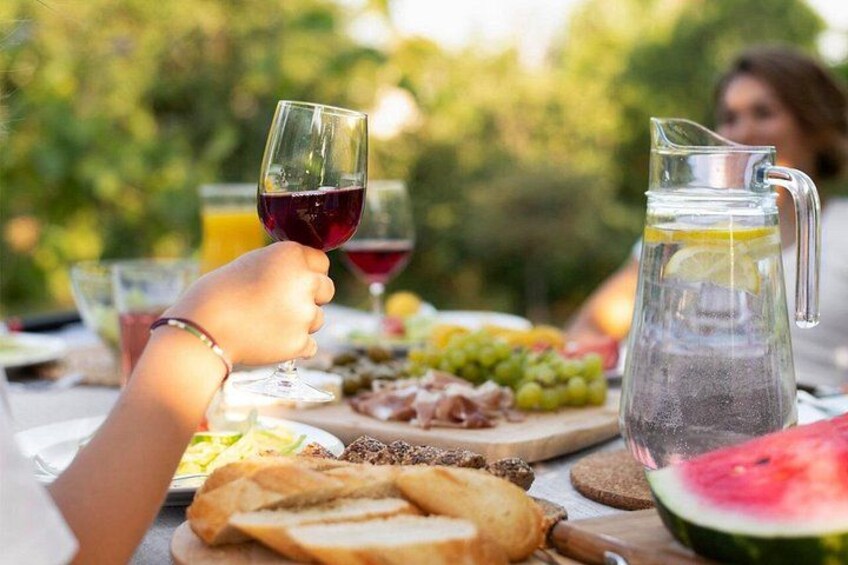 A picnic with food, a pitcher, and a glass of red wine. 1