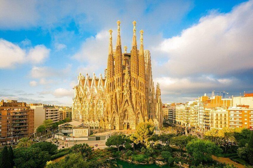 Sagrada Familia med sina detaljrika torn, omgiven av byggnader och grönska i stadsbilden. 3