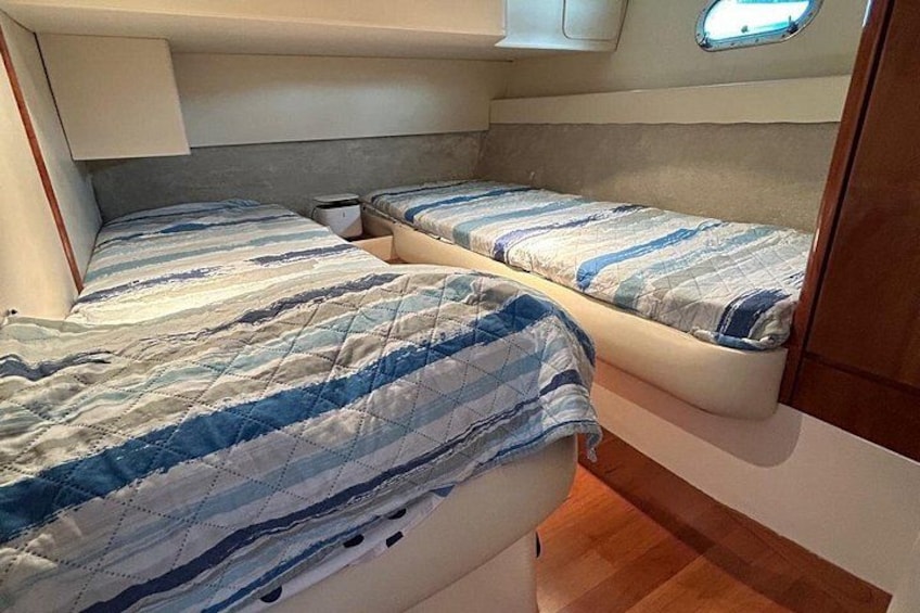 Un interior pequeño con dos camas, una ventana discreta y suelo de madera. 3