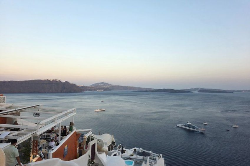 A calm sea with boats, a ship's deck, and distant land. 3