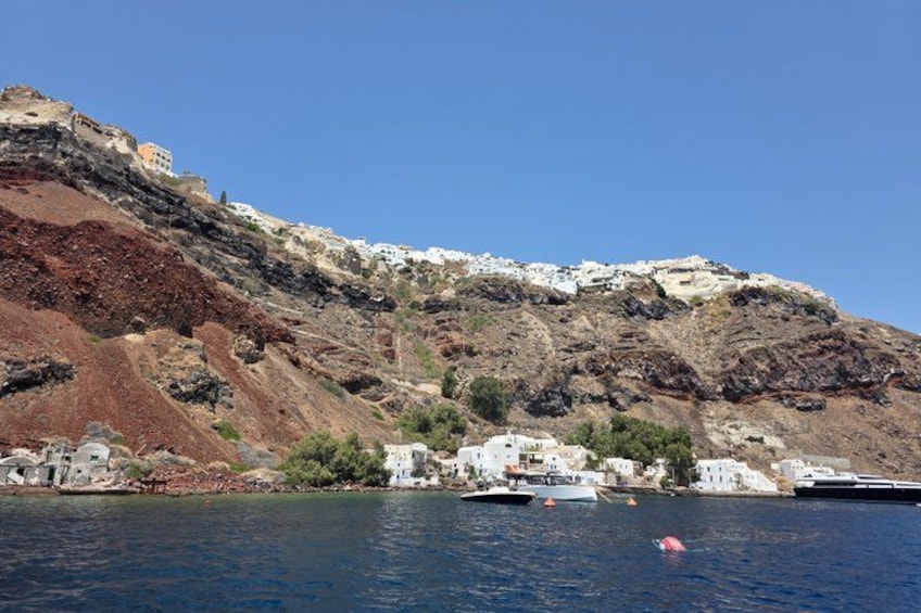 A coastal town with white buildings, a rocky hillside, and boats on the water. 4