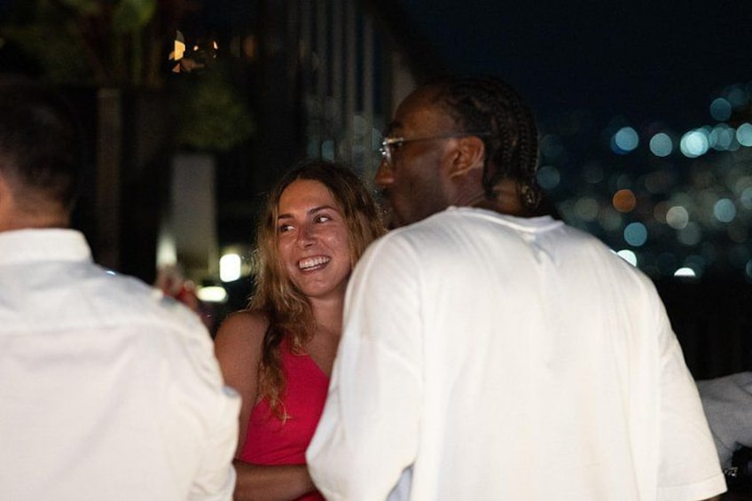A group of people outdoors at night, with city lights in the background. 2