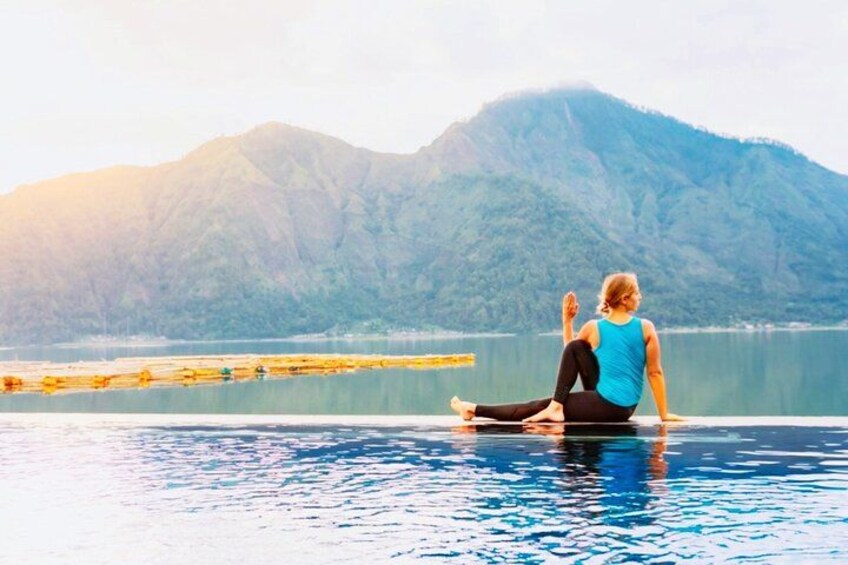 A person sitting on a dock by a lake with mountains in the background. 5