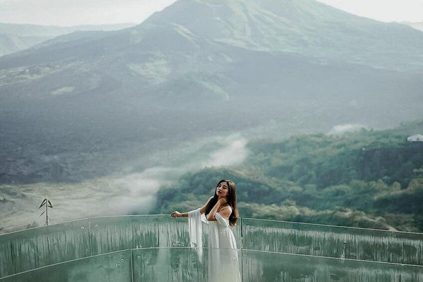 A person standing on a glass bridge with a mountainous landscape in the background. 4