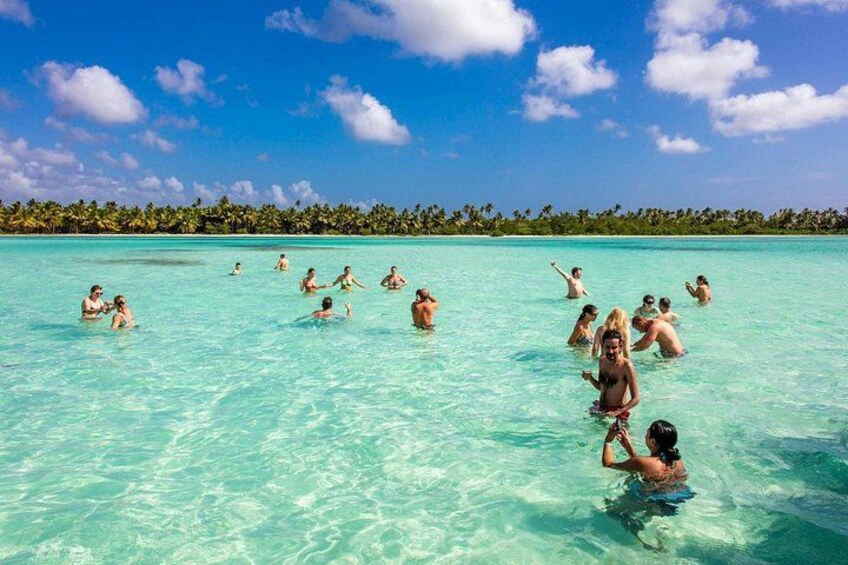 Una spiaggia tropicale con acque cristalline turchesi, palme e persone che nuotano e si rilassano. 1