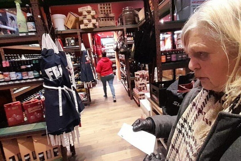 Una persona sostiene un papel en un pasillo de tienda con estantes llenos de diversos artículos. 4