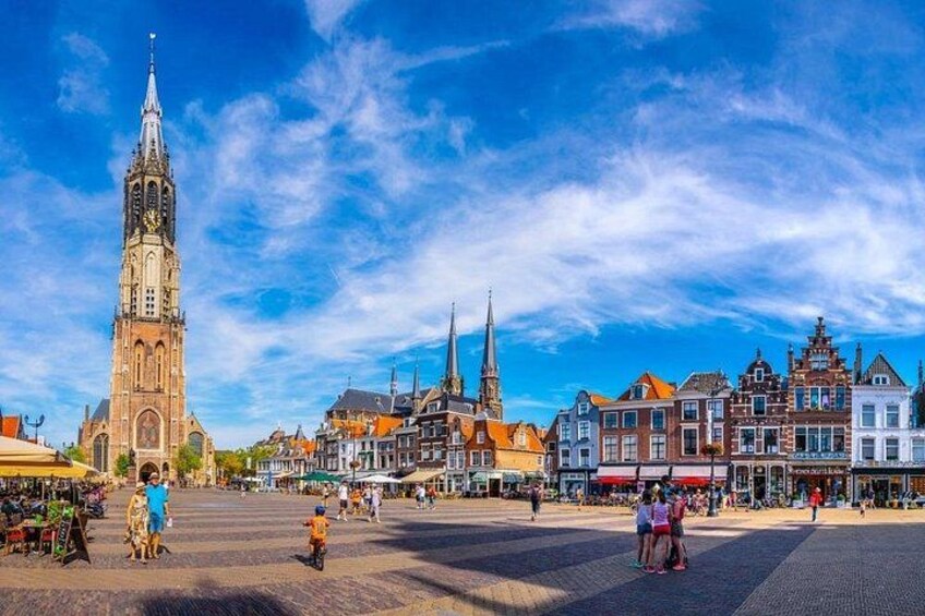 A historic town square with a prominent church tower, traditional buildings, and a cobblestone street. 4