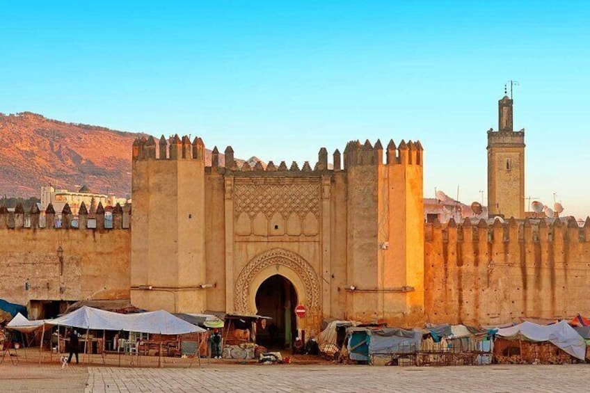 Entrada a una ciudad histórica amurallada, con un gran arco y una torre de vigilancia. 3