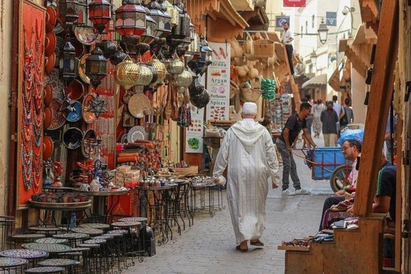Una calle estrecha flanqueada por tiendas que venden cerámica y textiles. 1