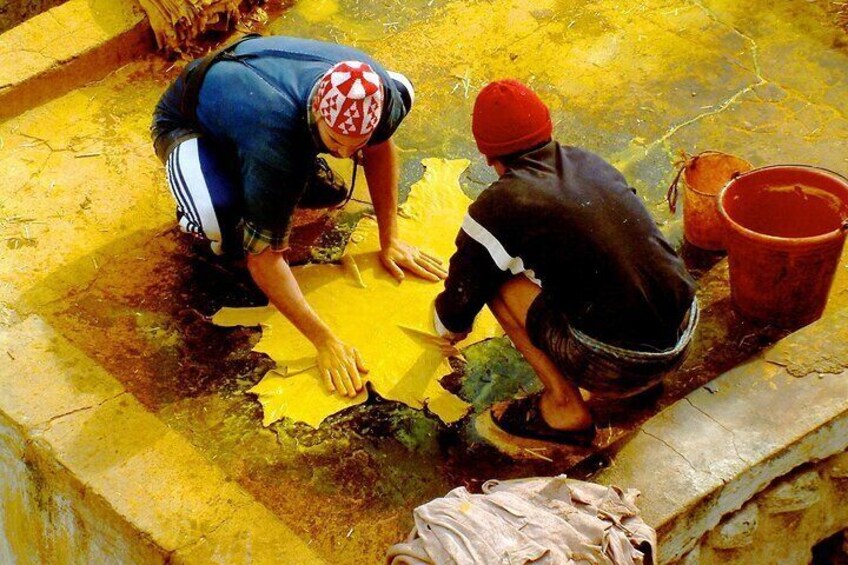 Dos personas trabajando sobre una superficie amarilla, posiblemente limpiándola o reparándola, con un cubo rojo cerca. 4
