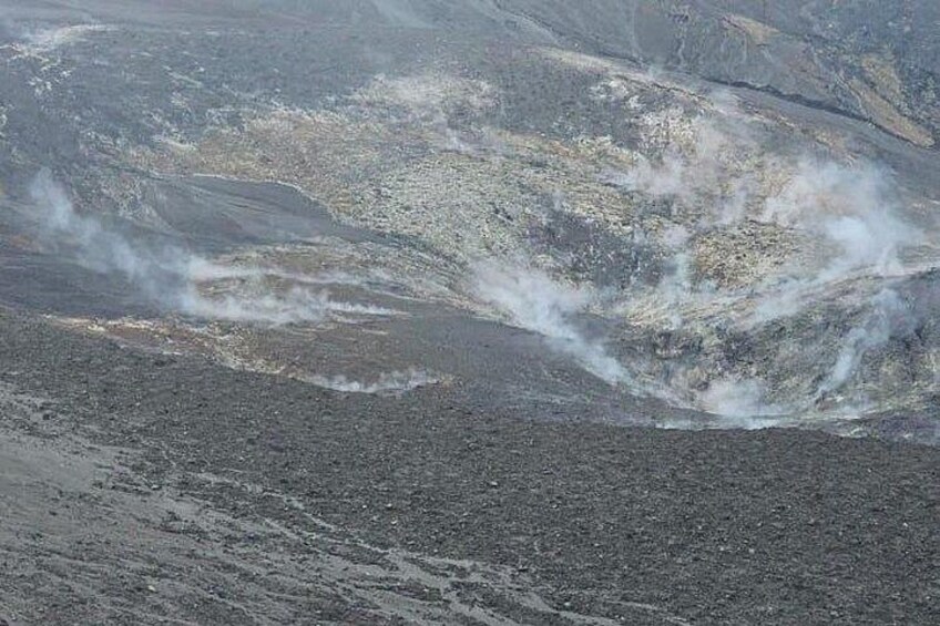 Un paysage volcanique où l’on peut observer une coulée de lave et de la vapeur s’élevant du sol. 2