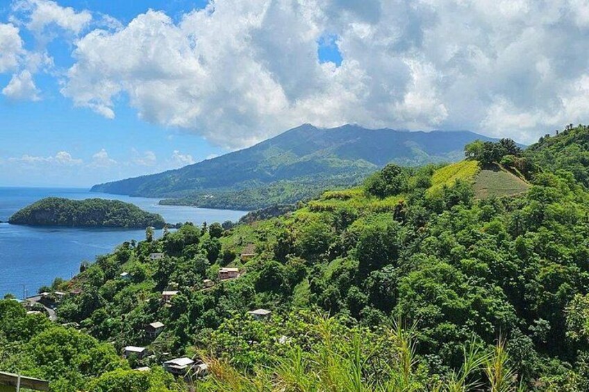 Un paysage montagneux, avec une végétation luxuriante, un lac et un volcan qui se profile à l’horizon. 3