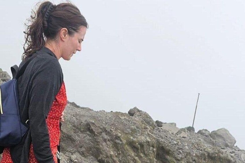 Une personne se tient debout sur un terrain rocheux, un sac à dos sur le dos, et contemple un paysage accidenté. 4