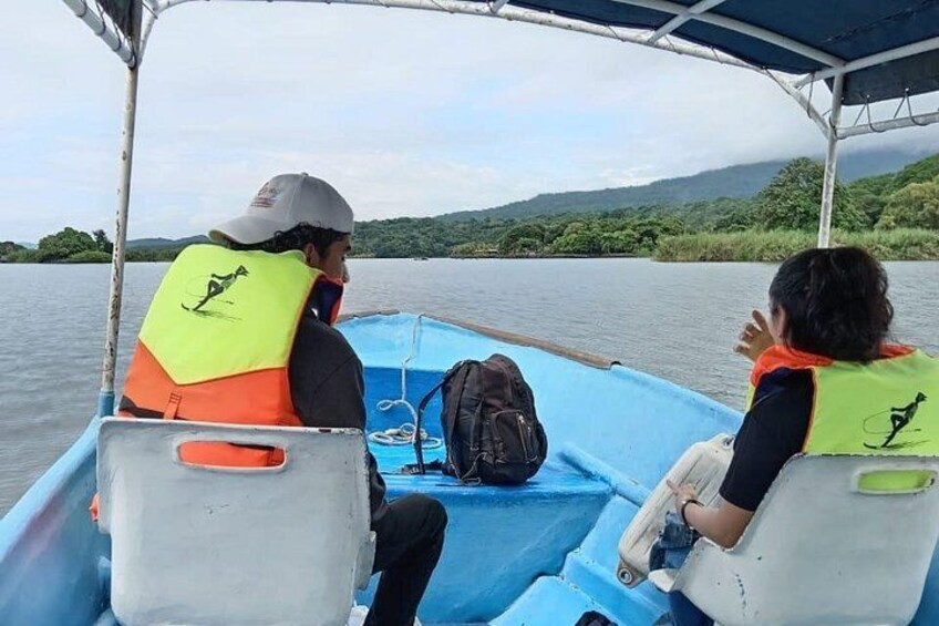 Two people on a boat wearing life jackets, with a backpack on the seat. 5