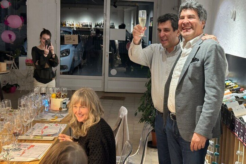 En person holder et vinglas, et bord med vinglas og en menu. 5
