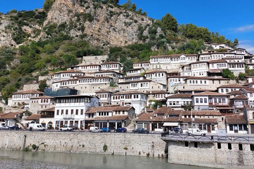 A hillside settlement with terraced houses, a stone wall, and a body of water. 1