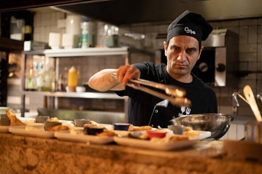 A chef in a kitchen with various dishes and cooking utensils. 2