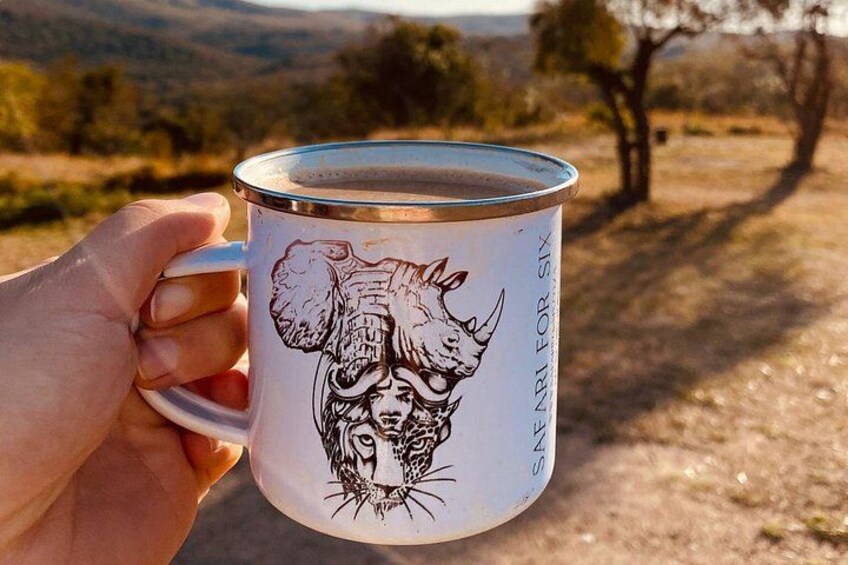 Una mano che tiene una tazza con la faccia di un leone e la scritta 'SAFARI FOR SIX'. 4