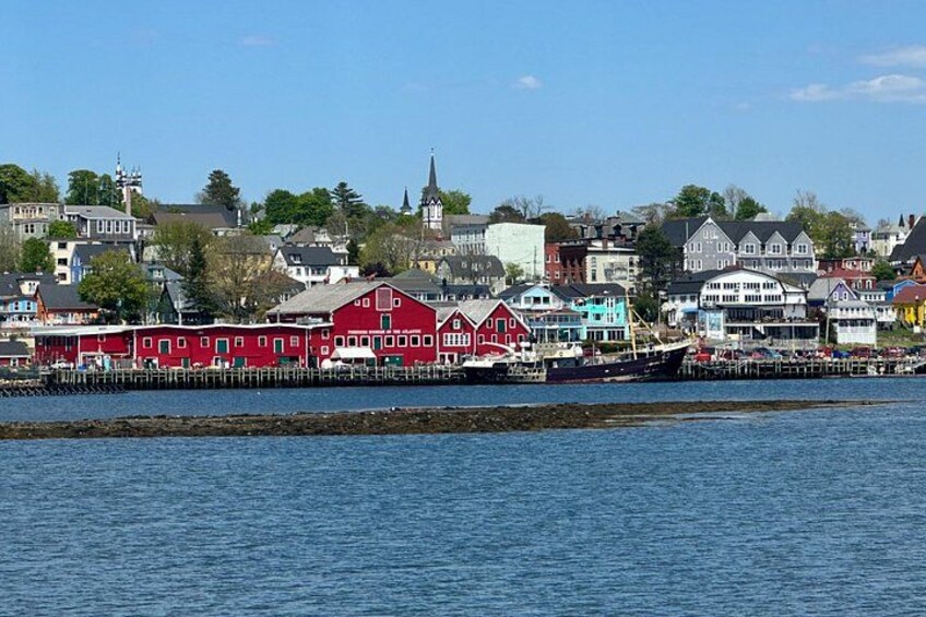 A waterfront town with colorful buildings, a church steeple, and a dock with boats. 3