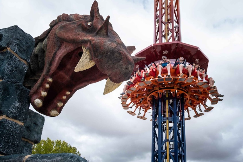 A roller coaster with a large dinosaur head sculpture at the base. 1