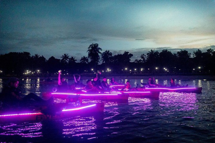 People on boats with illuminated paths on a body of water at dusk. 2