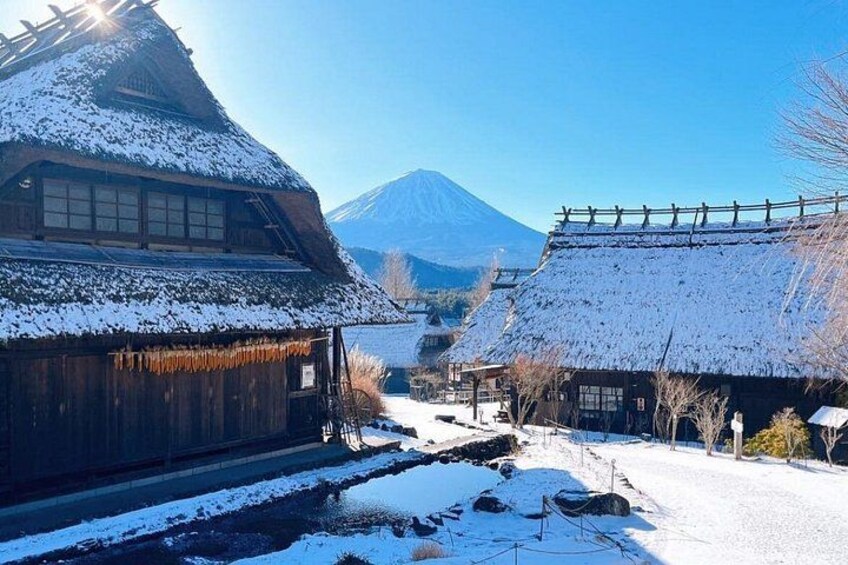 A snow-covered village with traditional wooden houses, a mountain in the background, and a clear sky. 5