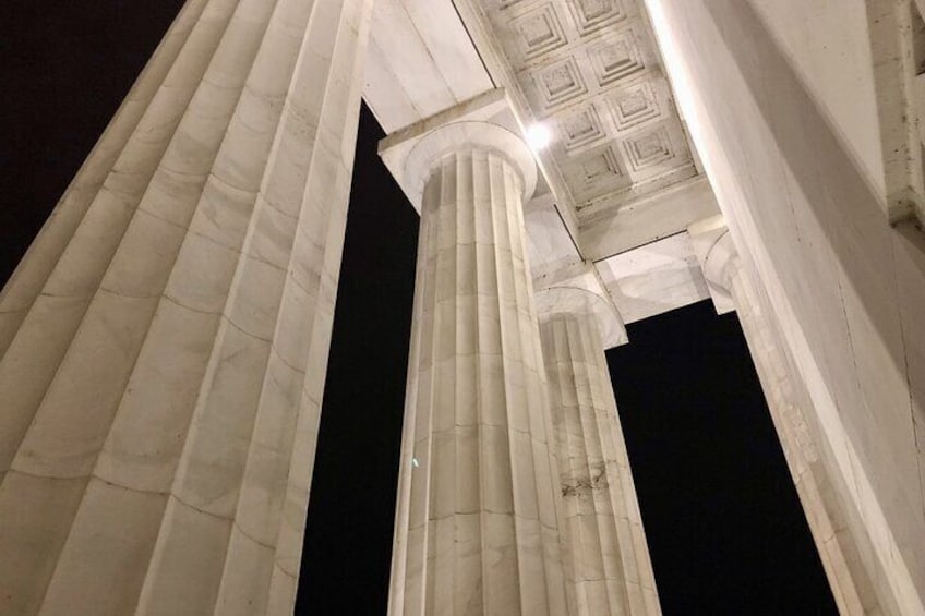 A night view of a classical building with tall, white columns and a detailed ceiling. 1