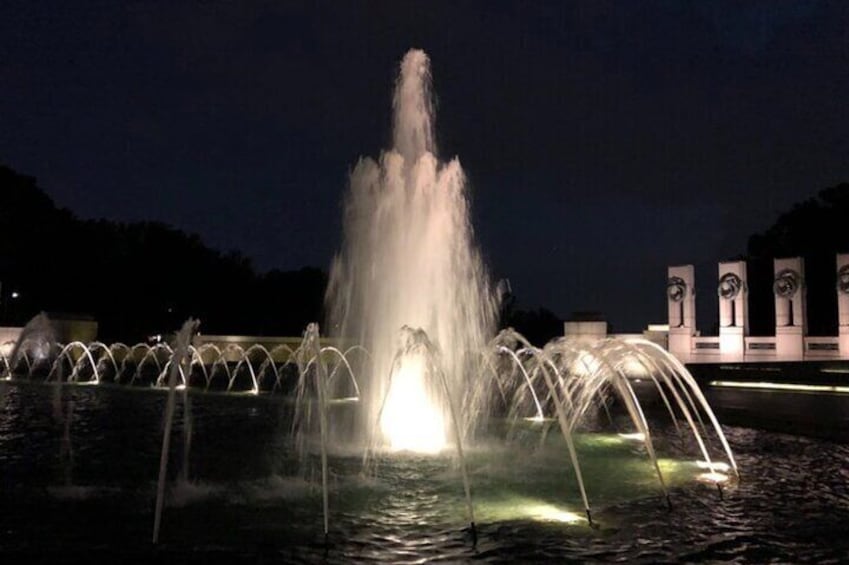 A nighttime fountain with illuminated water jets and arches. 5