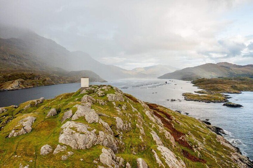 A coastal landscape with rocky terrain, a small white building, and a body of water. 2