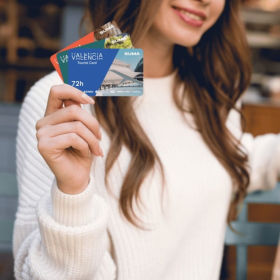 A person holding a tourist card with 'VALENCIA' and 'SUMA' logos, indicating a location in Valencia, Spain. 2