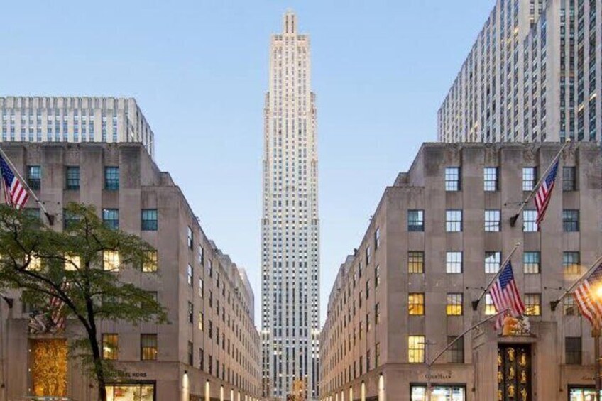 Una strada cittadina con palazzi alti, bandiere americane e cielo sereno. 1
