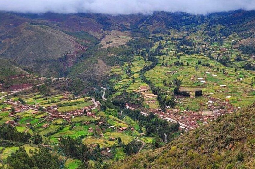 A mountainous landscape with terraced fields, a winding road, and a small building. 3