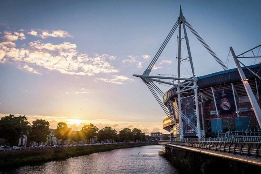 Un stade avec une rivière au premier plan et un coucher de soleil en arrière-plan. 1