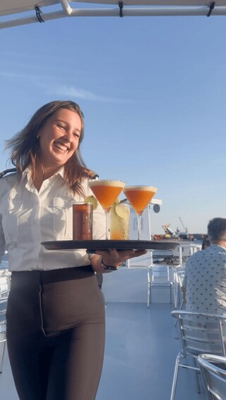 A person carrying a tray with drinks and a bottle on a boat deck. 2