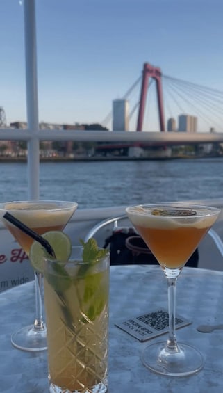 Two cocktails on a table with a view of a bridge and cityscape. 3